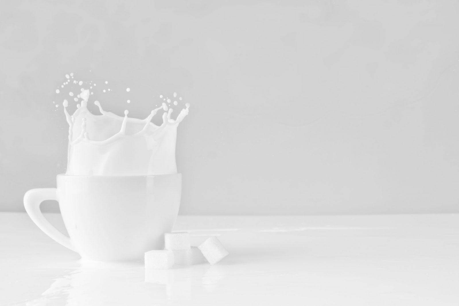 Milk splash in white coffee cup