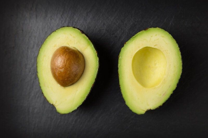 Two halves of an avocado on a black background.